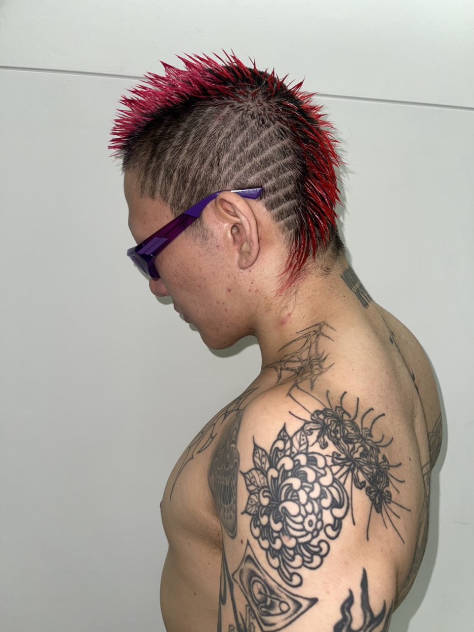 Red spiked mohawk with a striped fade, seen in profile